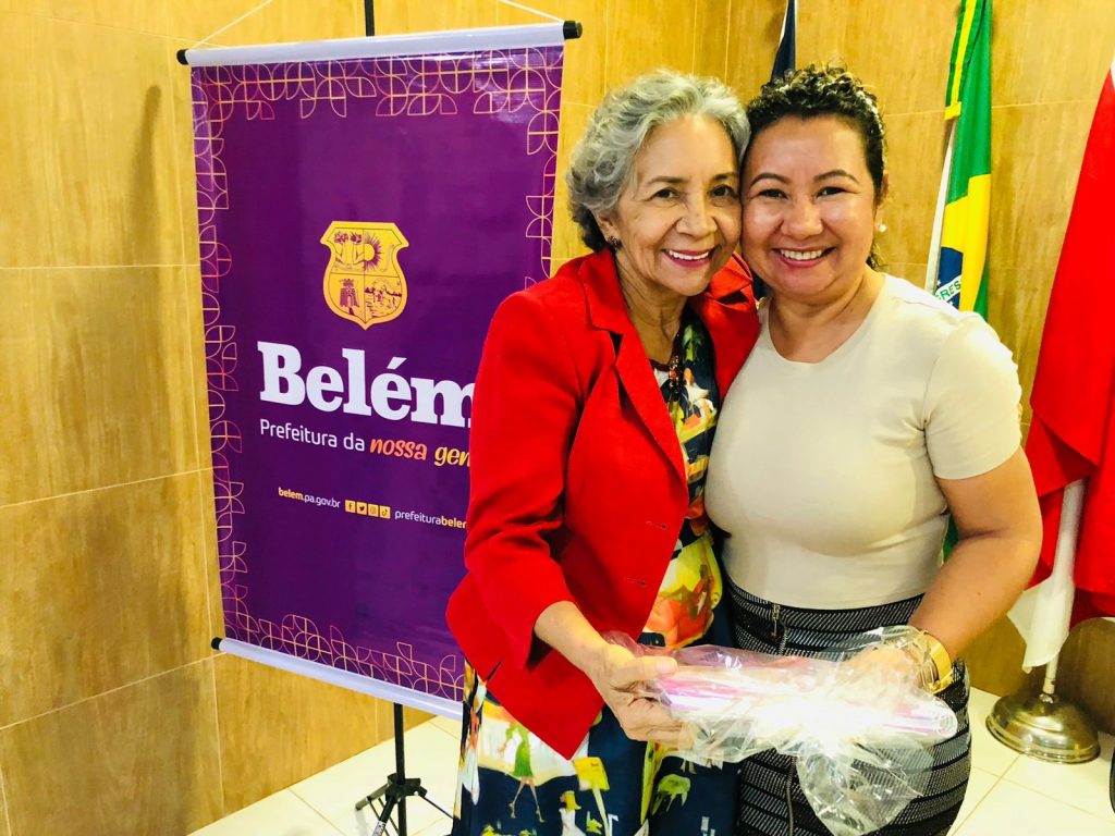 Uma das autoras do livro, a servidora da Ejai Ruth Lopes entrega um exemplar para a titular da Semec, Araceli Lemos (blusa vermelha): livro importante para a vida