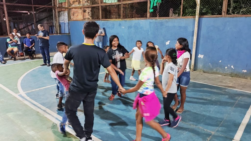 Crianças Warao, filhos dos estudantes da Escola Helder Fialho, participam de atividades na quadra, enquanto seus pais e mães estão em sala de aula