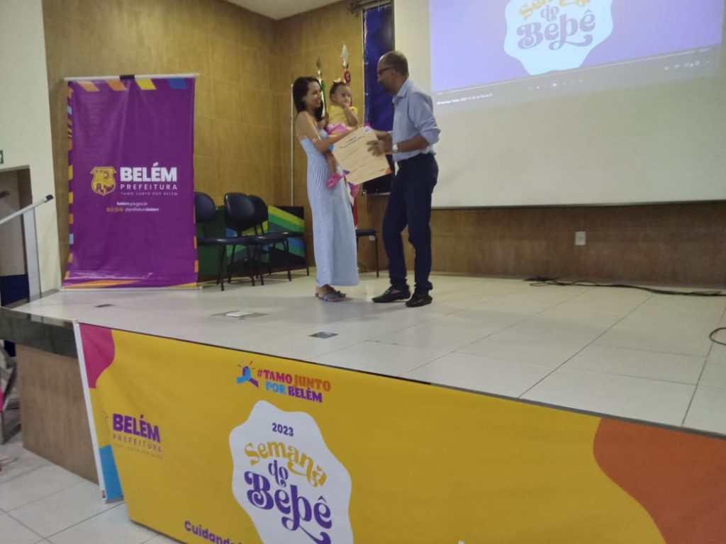 A pequena Lívia no colo da mãe Jullyane recebendo o selo "Bebê Prefeita"